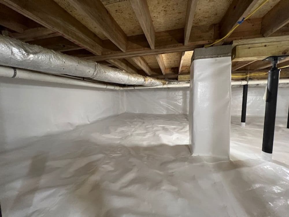 Cleansed crawl space with white plastic liner and exposed beams for moisture control.