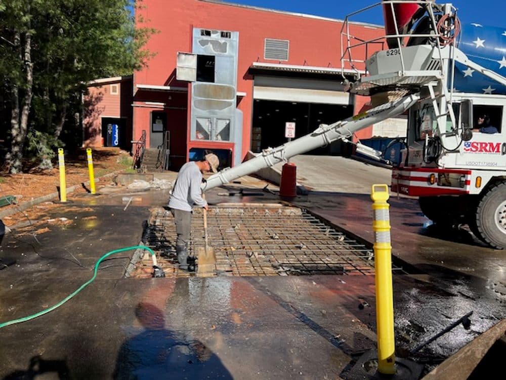 Construction worker preparing concrete at a job site with a concrete mixer truck.