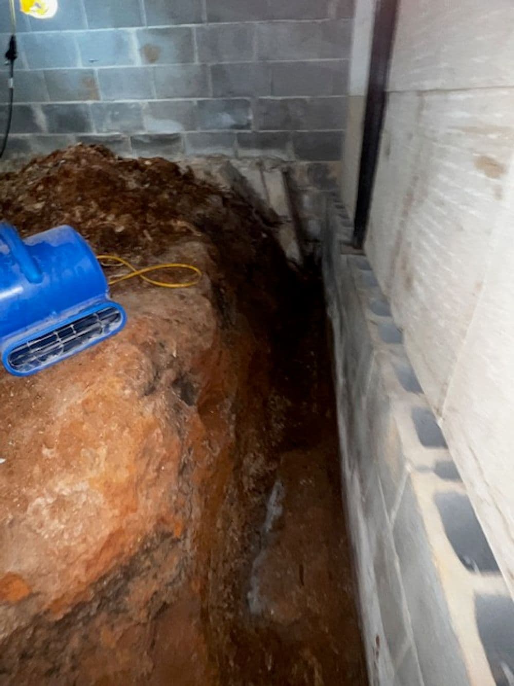 Excavated area in basement showing soil and construction materials with tools.